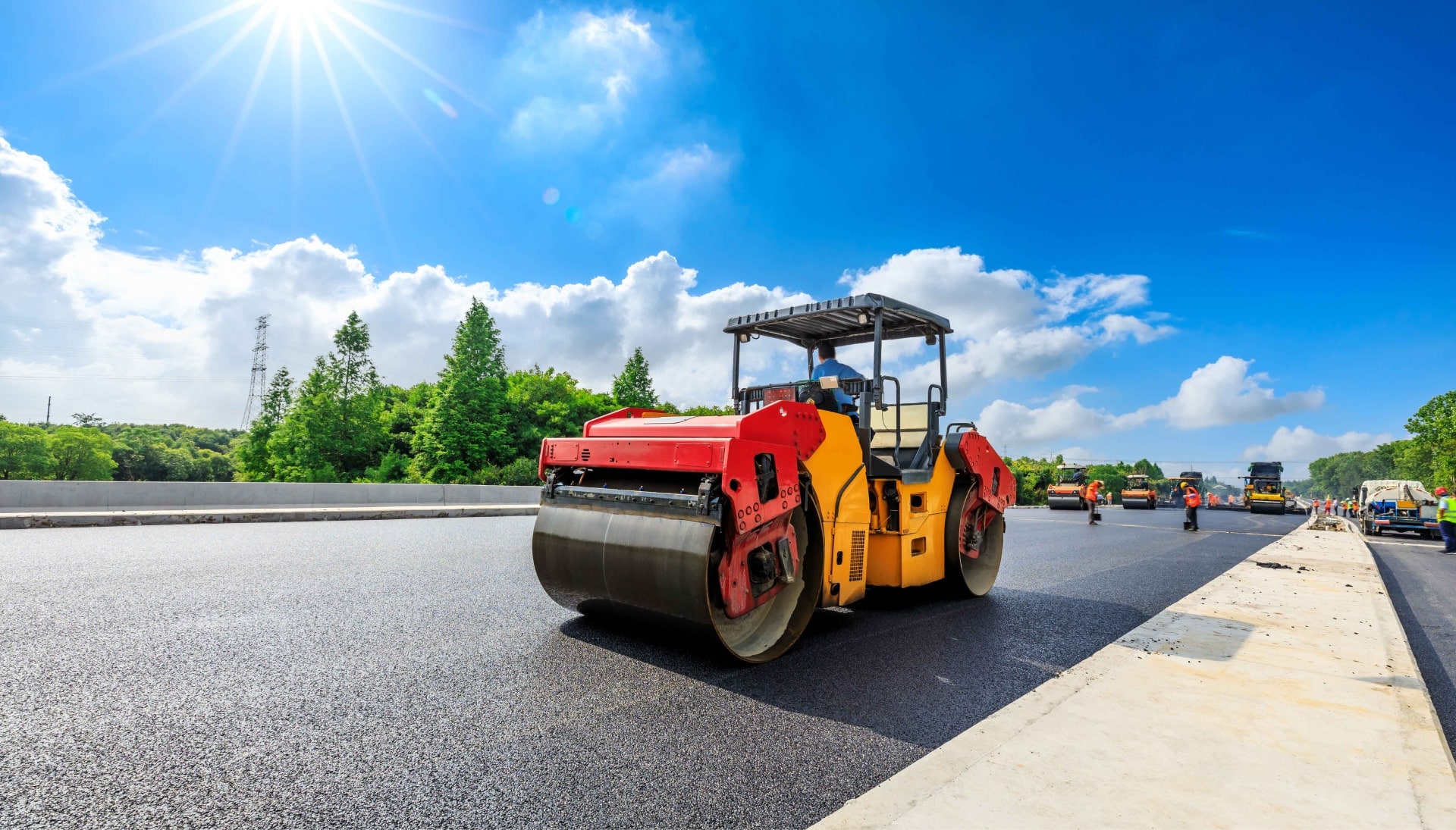 A team of construction workers operating heavy machinery, meticulously laying down fresh, smooth asphalt on a newly constructed road in San Antonio, with steam rising from the hot surface.